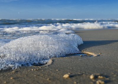 close-up van zeeschuim op strand langs de vloedlijn