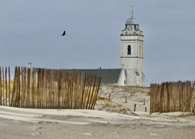 strand katwijk met houten hek en zicht op oude kerk