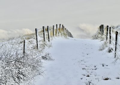 witte strandopgang met dik pak sneeuw wandelend richting strand