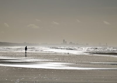 zilverwit op strand met glittering op het water en een schelpenzoeker op het zuidstrand van katwijk aan zee