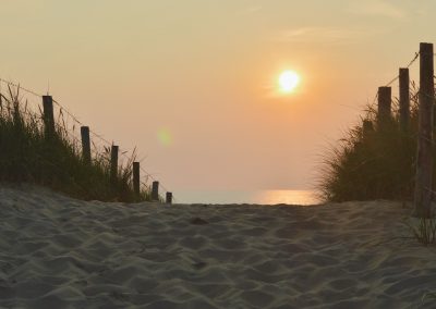 zonsondergang bij strandopgang in gouden uur richting zee